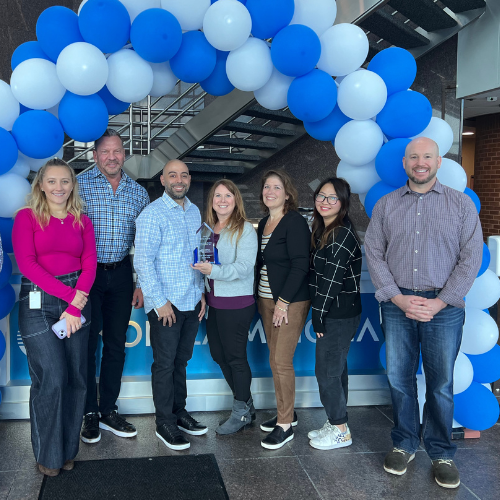 Konica Minolta employees stand under an arch made of balloons.